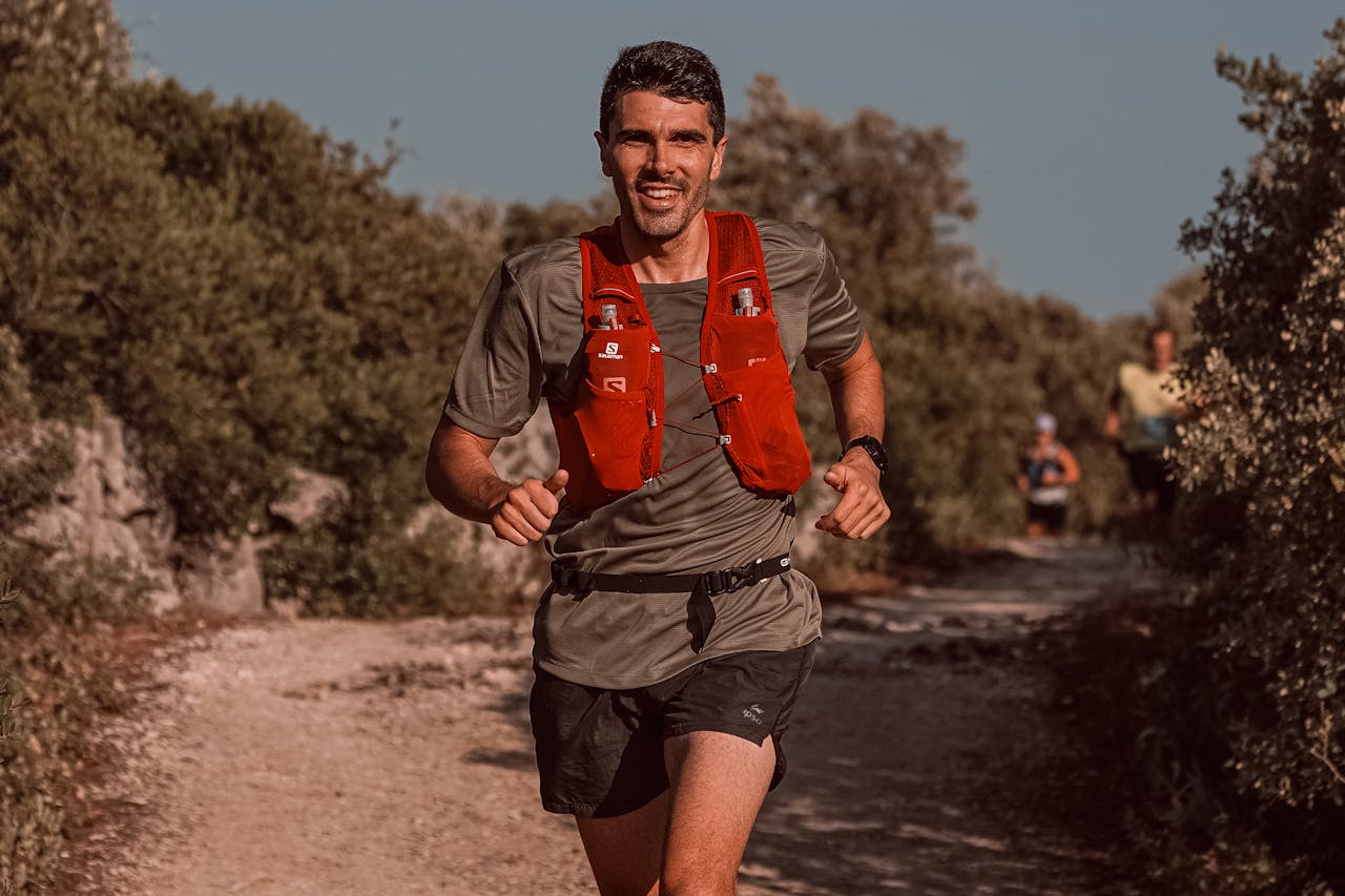 Smiling man jogging on a rural footpath, enjoying outdoor running in sportswear.